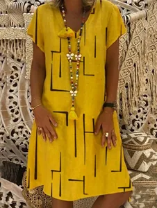 Detail of ginger yellow V-neck cotton dress with black geometric lines and tassel necklace