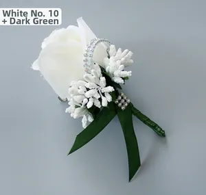 Detail of white artificial rose boutonniere with dark green ribbons and rhinestone accents