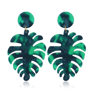 Macro detail of green monstera leaf earrings with faux marble resin texture on white backdrop