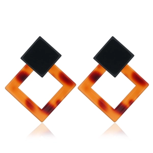 Macro view of C-shaped geometric resin earrings featuring tortoiseshell pattern and studs