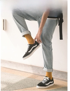 Close-up of mustard yellow cotton crew socks styled with black sneakers and blue jeans