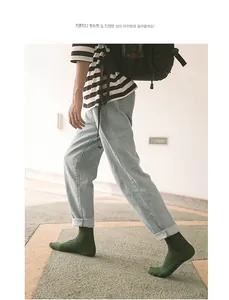 Close-up of dark green ribbed cotton mid-calf socks styled with casual denim jeans
