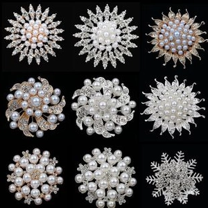 Macro detail of nine alloy brooches with sparkling rhinestones and white pearls