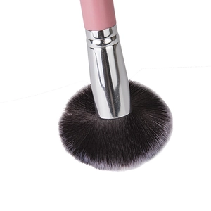 Macro detail of dense black bristles and pink handle of a professional powder brush