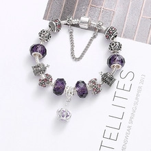 Close-up of silver unicorn charm bracelet with purple glass beads and crown charms
