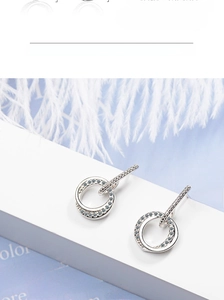 Detailed close-up of silver double-hoop earrings featuring pavé set zircons on a white stand