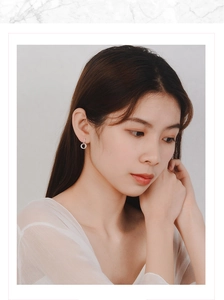 Close-up of silver interlocking hoop earrings worn by a model in a minimal setting