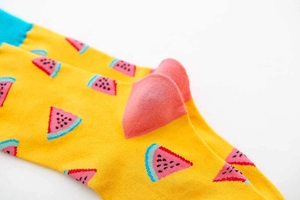 Detail of knit crew sock with yellow base, watermelon patterns, and pink heel accent