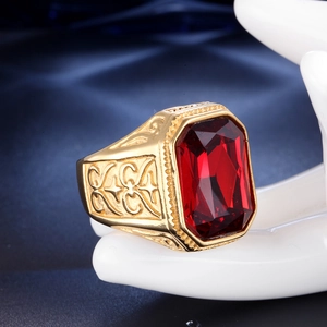 Dettaglio macro dell'anello punk dorato da uomo con grande gemma rossa di forma quadra