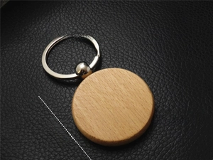 Detail of 40mm round beech wood keychain with silver metal ring on black leather