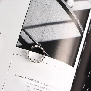 Detailed close-up of a silver wavy triple-layer ring on a stylish magazine page