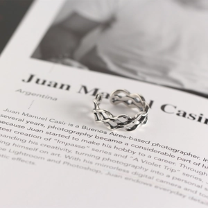 Detailed close-up of a silver Mobius braided ring resting on an open magazine page
