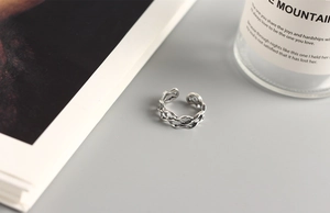 Macro detail of silver layered wave ring featuring an intricate woven texture and open band