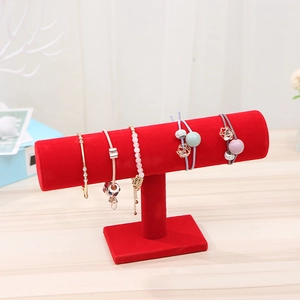 Red velvet T-bar display stand showcasing metal bracelets and hair accessories on wood