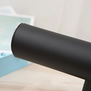 Macro view of black faux leather texture on cylindrical bracelet and watch display stand