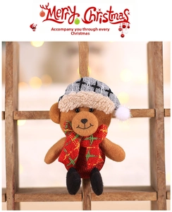 Close-up of a brown plush Christmas teddy bear ornament with grey knit hat and scarf