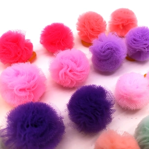 Close-up of colorful tulle pom-pom pet hair ties in pink, purple and orange tones