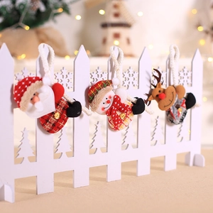 Three Christmas plush ornaments including Santa, Snowman and Reindeer on white fence