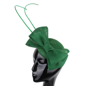Close-up of green mesh fascinator with large bow and elegant feather accents on mannequin