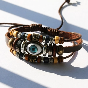 Close-up of multilayer leather bracelet with turquoise beads and evil eye charm in sunlight