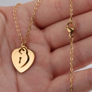Handheld shot of gold double-layered heart necklace with a keyhole lock pendant