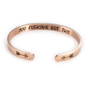 Macro detail of rose gold 6mm stainless steel cuff bracelet with engraved slogan
