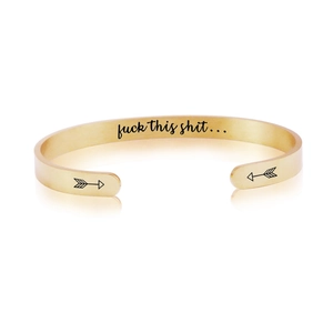 Detail of gold C-shape stainless steel cuff featuring arrow ends and interior engraving