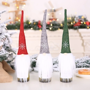 Three Nordic Christmas gnome wine bottle covers in red, grey, and green with plush beards