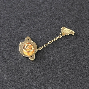 Golden planet brooch back view with butterfly clasp and small chain on black texture