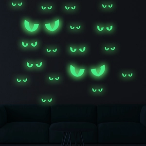 Luminous green glowing cat eyes stickers on a dark wall for Halloween spooky atmosphere