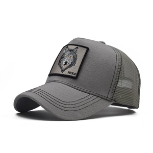 Detail of embroidered wolf patch on a grey cotton mesh trucker hat with decorative stitching