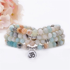 Detail of 108 Mala Amazonite prayer beads with silver Om pendant on white backdrop