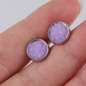 Macro shot of 8mm purple crystal stud earrings with silver metal base on fingertip