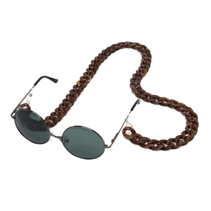 Detailed view of dark amber tortoiseshell acrylic eyewear chain on black sunglasses
