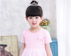 Detail of a sparkling crystal crown hair clip on a pink lace princess dress