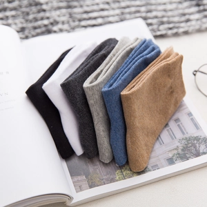 Men's premium cotton crew socks in six solid colors neatly stacked on a magazine
