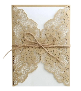 Macro view of laser-cut butterfly invitation with rustic jute twine bow and cream lace texture