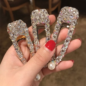 Close-up of three sparkling crystal hair clips featuring rhinestones and a white pearl accent