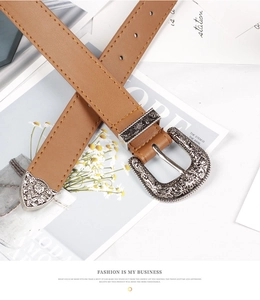 Détail de ceinture en cuir marron avec boucle sculptée argentée et coutures de style Western