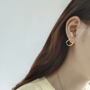 Close-up of a model wearing irregular hollow golden sterling silver hoop earrings