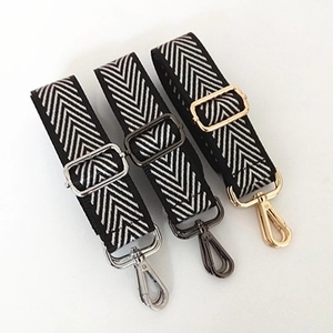 Detail of woven nylon bag straps with black and white V-pattern and colorful metal hooks