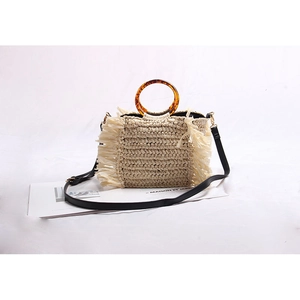 Beige woven straw beach bag with amber ring handle, black strap and side tassel details