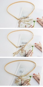 Detail of gold metal waist chain belt featuring charms and decorative tassels