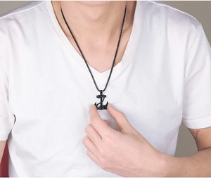 Gros plan d'un collier pendentif ancre noir en acier pour homme porté par un mannequin