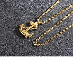 Gros plan d'un collier pendentif ancre dorée avec sa chaîne gourmette carrée assortie