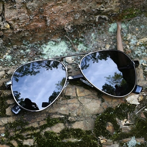 Classic gunmetal aviator sunglasses with black polarized lenses on a natural stone