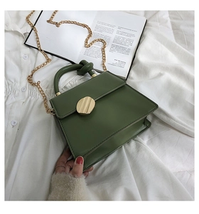 Close-up of green PU leather crossbody bag with golden chain and round metal buckle