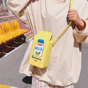 Chic banana milk carton crossbody bag with yellow strap in a trendy outdoor setting
