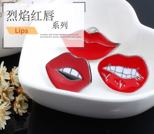 Three-piece red enamel lip brooches displayed in a heart-shaped ceramic bowl