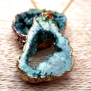 Vista macro del colgante de cristal de ágata azul-verde irregular con borde bañado en oro